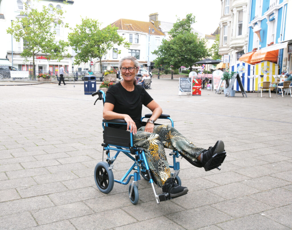 A happy woman in a transit wheelchair with an elevated leg rest